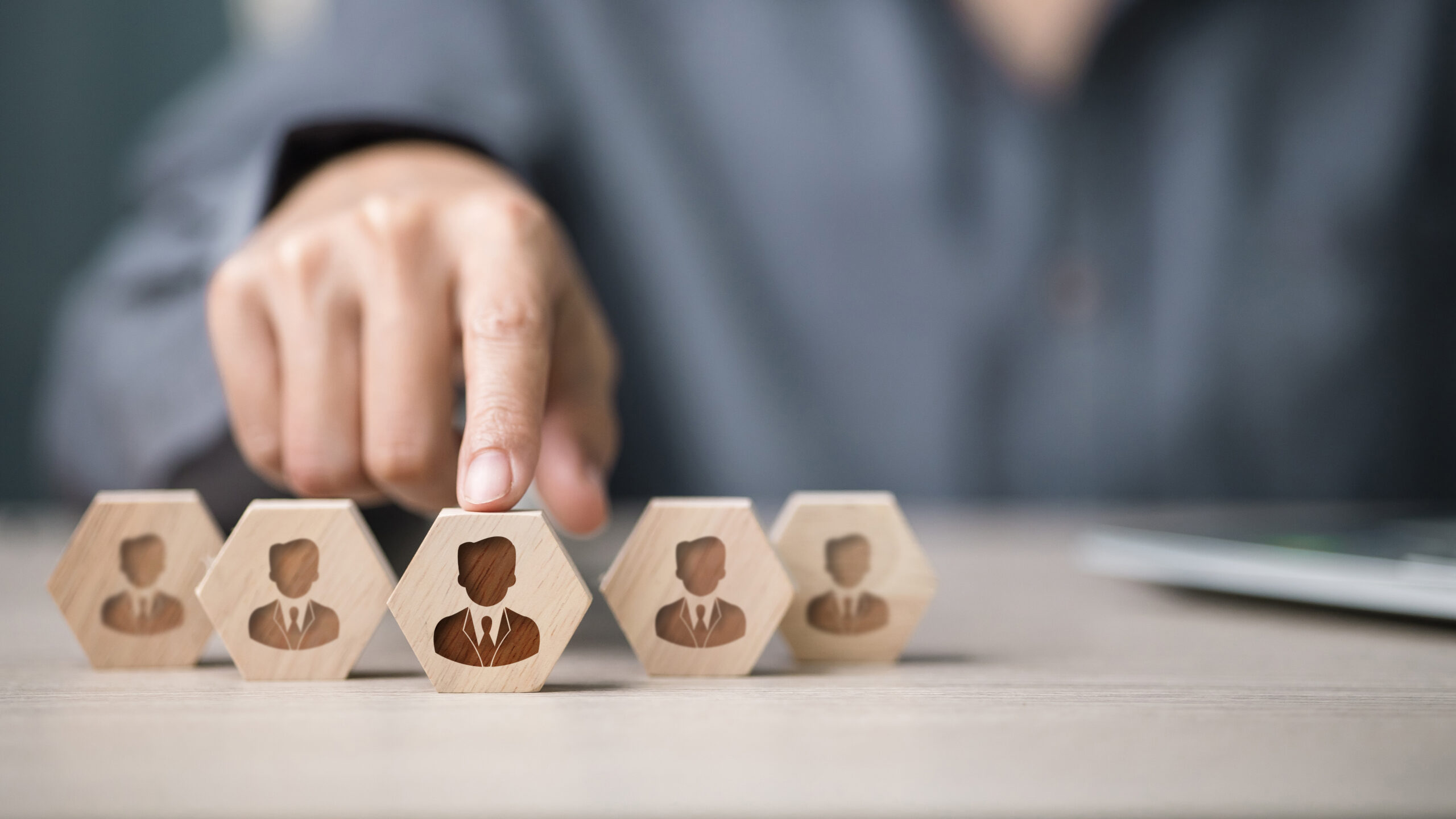 Main sélectionnant un bloc en bois symbolisant la détection d'un talent pour un plan de succession