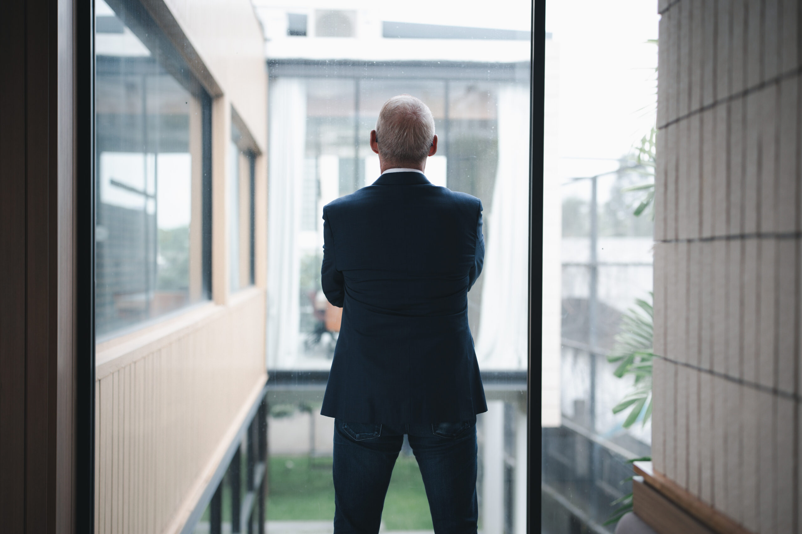 Dirigeant en pleine réflexion devant la fenêtre de son bureau, envisageant sa transition professionnelle